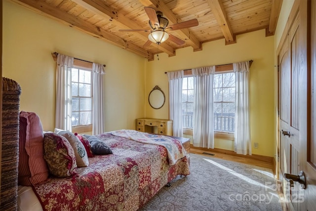 bedroom featuring ceiling fan, wood ceiling, beam ceiling, and multiple windows