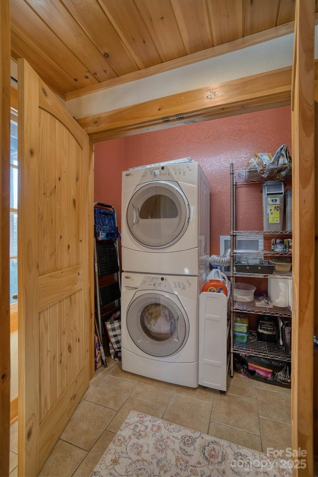 clothes washing area with stacked washing maching and dryer, wood ceiling, and light tile patterned floors