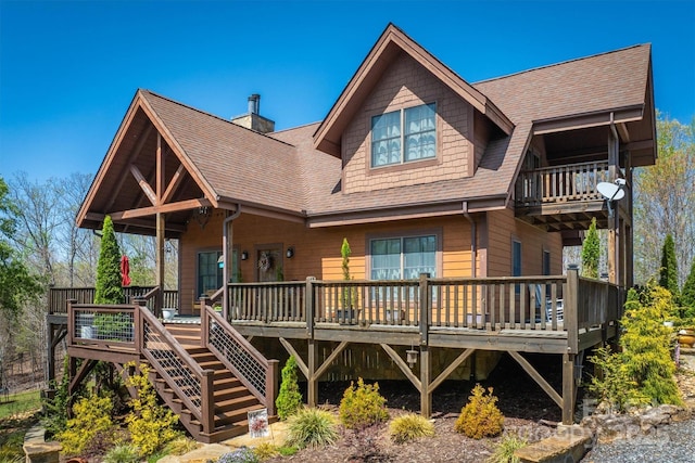 back of property featuring stairway, roof with shingles, and a deck