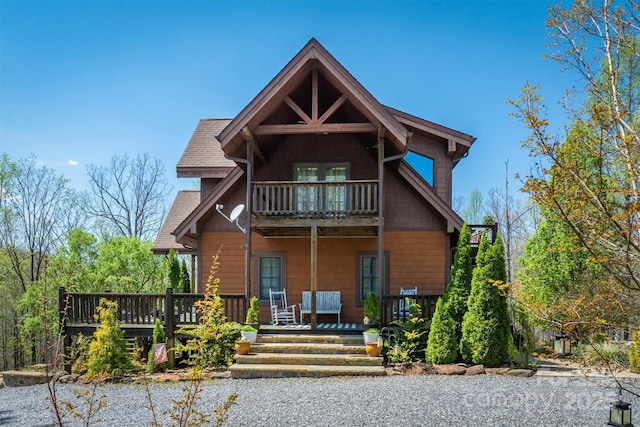 view of front of house featuring a shingled roof, covered porch, and a balcony