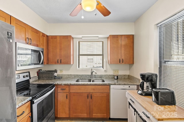 kitchen featuring stainless steel appliances, sink, a textured ceiling, and light stone counters