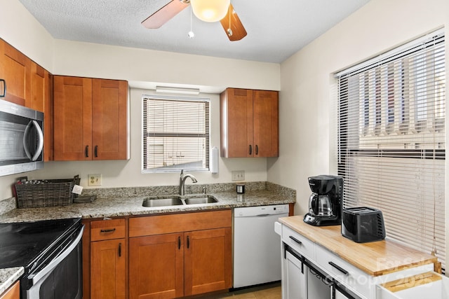 kitchen featuring light stone counters, sink, stainless steel appliances, and ceiling fan