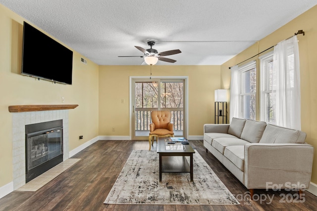 living room featuring dark wood-type flooring, ceiling fan, and a textured ceiling