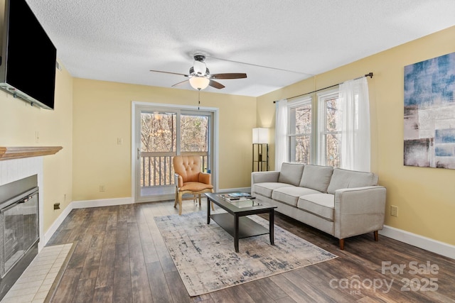 living room featuring ceiling fan, dark wood-type flooring, and a textured ceiling