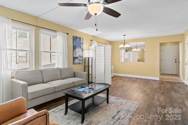 living room featuring ceiling fan with notable chandelier, hardwood / wood-style floors, and a textured ceiling