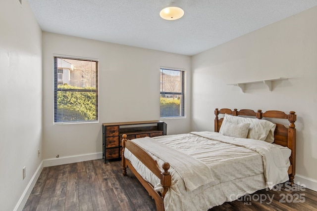 bedroom featuring multiple windows, dark wood-type flooring, and a textured ceiling