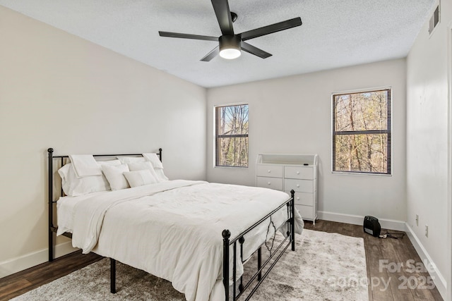 bedroom featuring dark wood-type flooring, ceiling fan, and a textured ceiling