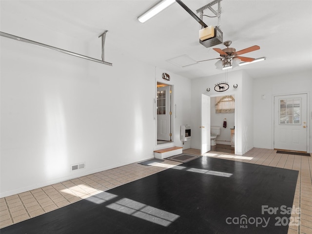 garage featuring ceiling fan, heating unit, and a garage door opener