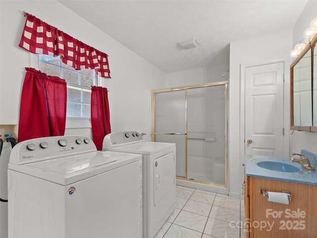 laundry room featuring washer and clothes dryer, sink, light tile patterned floors, and a textured ceiling