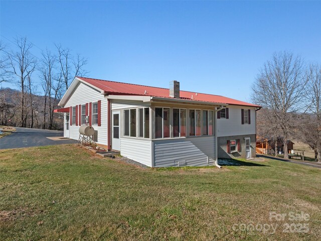 back of house featuring a sunroom and a lawn