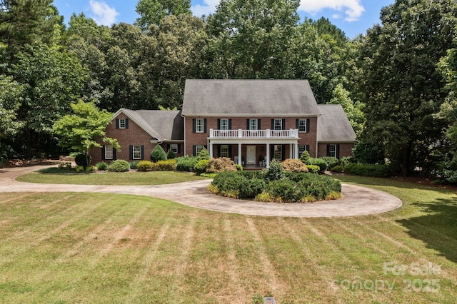 colonial-style house with a balcony and a front lawn