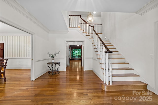 stairway with hardwood / wood-style flooring, a chandelier, and crown molding