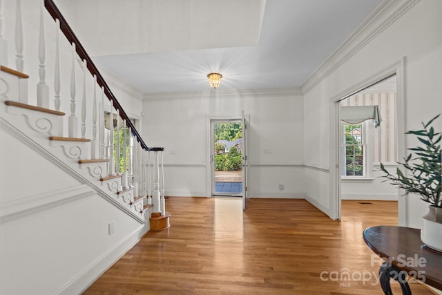 entrance foyer featuring wood-type flooring, a healthy amount of sunlight, and ornamental molding