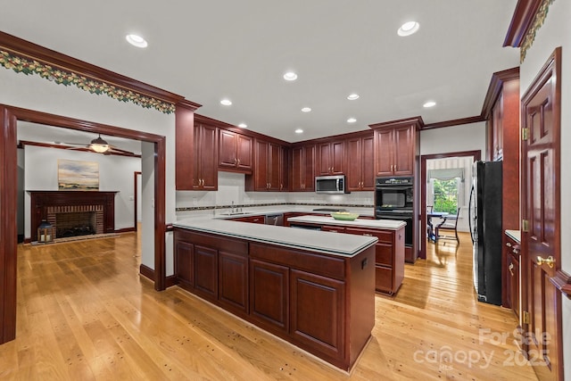 kitchen featuring black appliances, crown molding, a fireplace, tasteful backsplash, and light hardwood / wood-style flooring