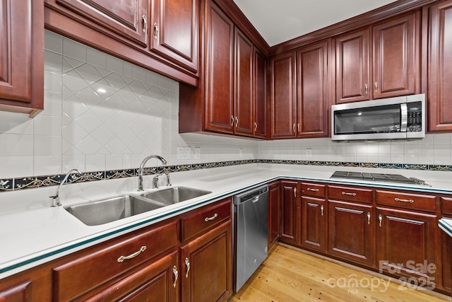 kitchen with sink, light hardwood / wood-style flooring, decorative backsplash, and stainless steel appliances