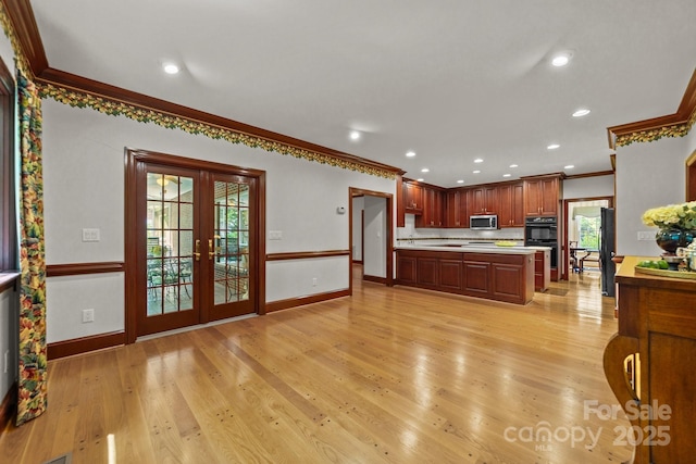 kitchen featuring black double oven, light hardwood / wood-style flooring, ornamental molding, and french doors