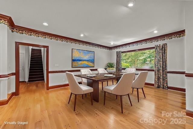 dining room with crown molding and light wood-type flooring