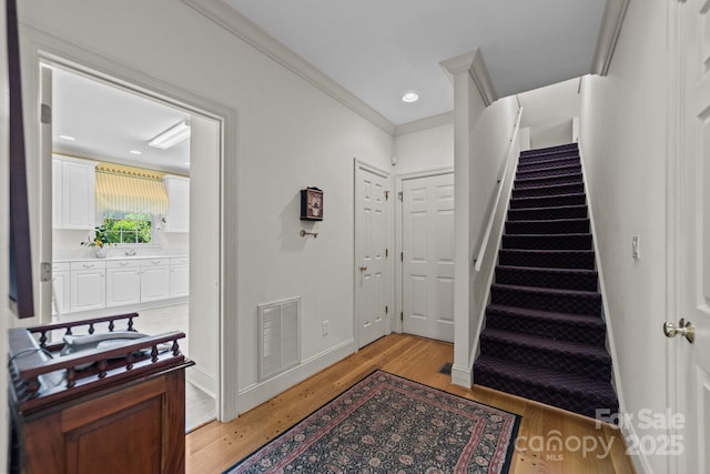 entryway featuring ornamental molding and light hardwood / wood-style flooring