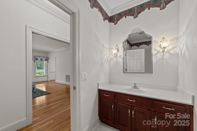 bathroom with crown molding, hardwood / wood-style floors, and vanity