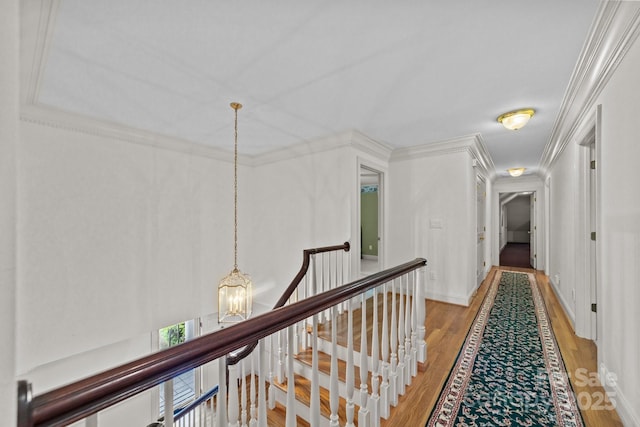 hall with crown molding, light wood-type flooring, and a notable chandelier