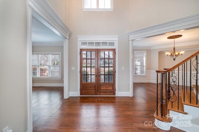 foyer entrance with crown molding, plenty of natural light, french doors, and a notable chandelier