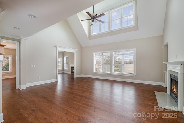 unfurnished living room with dark hardwood / wood-style flooring, a towering ceiling, and ceiling fan