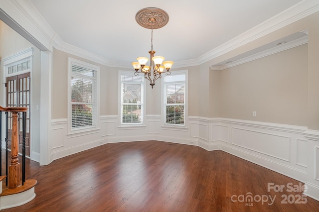 unfurnished dining area with crown molding, dark wood-type flooring, and a chandelier