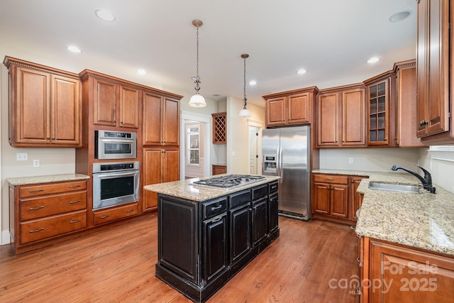 kitchen featuring sink, light stone counters, decorative light fixtures, a kitchen island, and stainless steel appliances