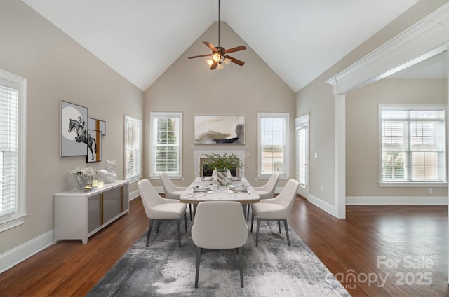 dining room featuring dark wood-type flooring, plenty of natural light, and high vaulted ceiling