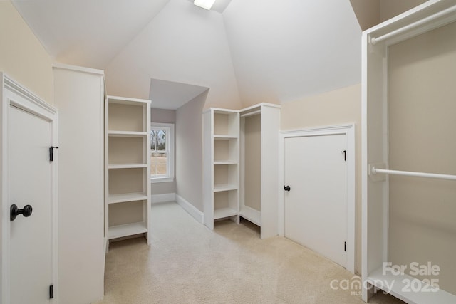 walk in closet with lofted ceiling and light carpet