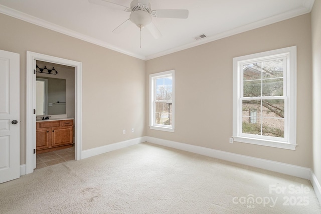 carpeted spare room featuring ceiling fan, ornamental molding, and plenty of natural light