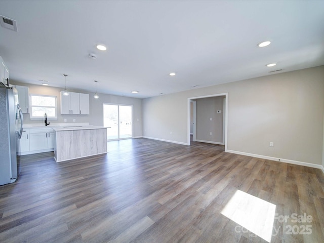 unfurnished living room with a barn door, sink, and wood-type flooring