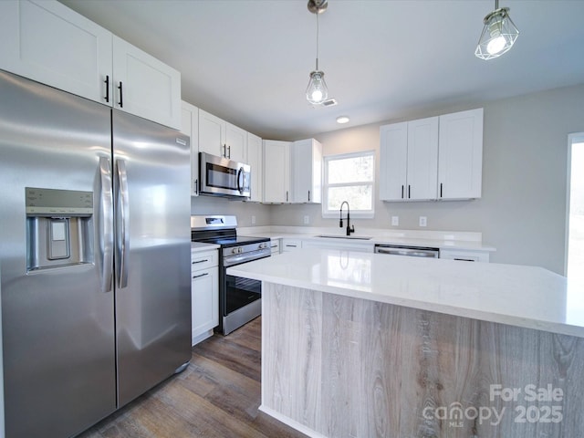 kitchen featuring appliances with stainless steel finishes, sink, pendant lighting, dark hardwood / wood-style flooring, and white cabinets