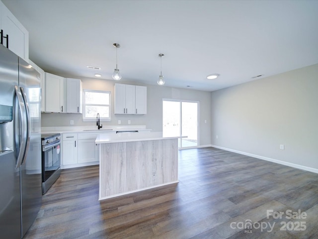 kitchen featuring a center island, decorative light fixtures, sink, appliances with stainless steel finishes, and white cabinets