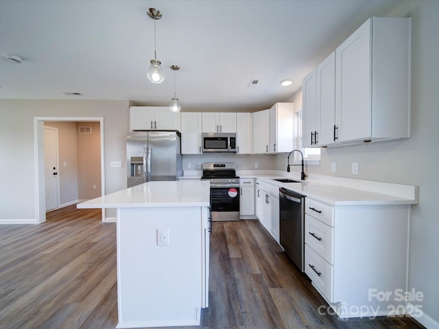 kitchen with sink, a center island, pendant lighting, stainless steel appliances, and white cabinets