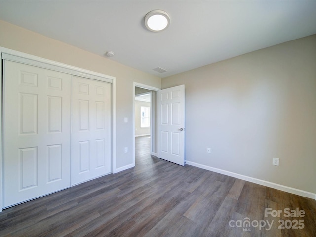 unfurnished bedroom with a closet and dark hardwood / wood-style flooring