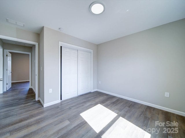 unfurnished bedroom featuring a closet and dark wood-type flooring