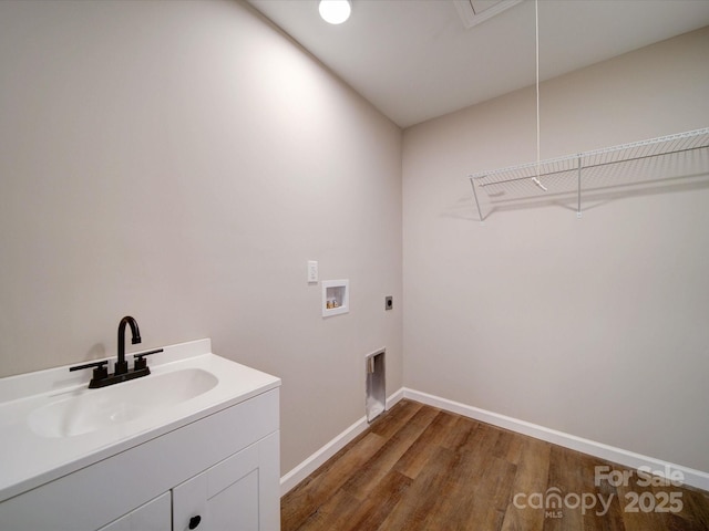 washroom with dark wood-type flooring, washer hookup, electric dryer hookup, sink, and cabinets