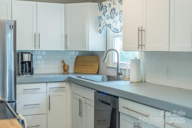 kitchen with white cabinetry, stainless steel fridge, dishwasher, and sink