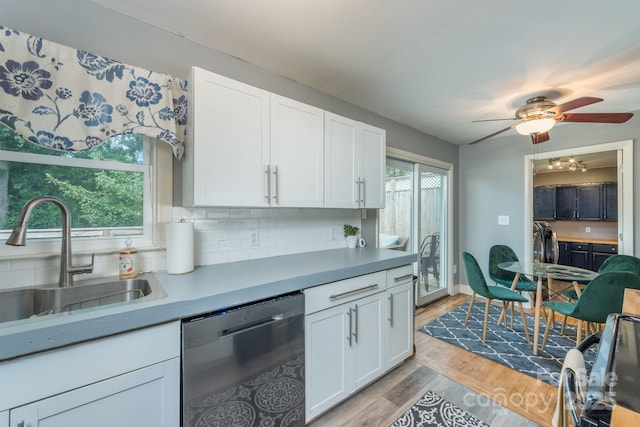 kitchen featuring sink, light hardwood / wood-style flooring, backsplash, white cabinets, and stainless steel dishwasher