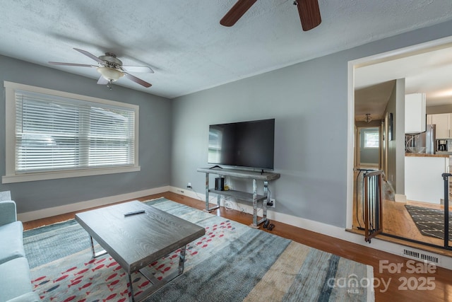 living room featuring ceiling fan, hardwood / wood-style floors, and a textured ceiling