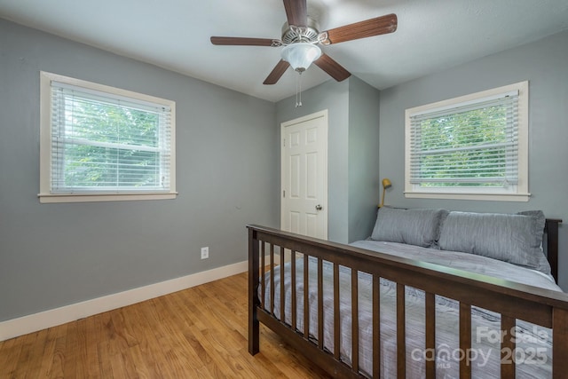 bedroom with multiple windows, ceiling fan, and light hardwood / wood-style flooring