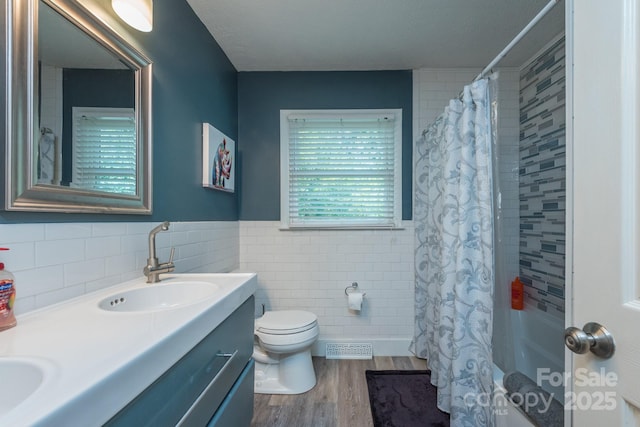 full bathroom with shower / bathtub combination with curtain, tile walls, hardwood / wood-style floors, vanity, and toilet