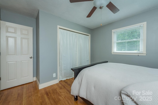 bedroom with hardwood / wood-style flooring, ceiling fan, and a closet