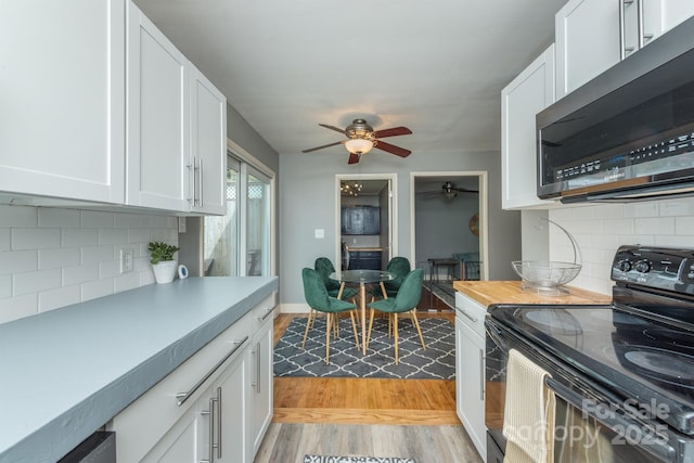 kitchen with light hardwood / wood-style flooring, ceiling fan, white cabinetry, black range with electric cooktop, and decorative backsplash