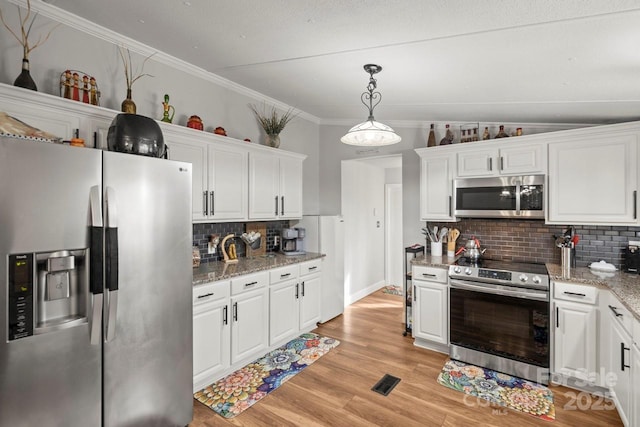 kitchen with pendant lighting, stainless steel appliances, light stone counters, tasteful backsplash, and white cabinets