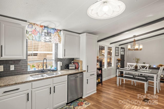 kitchen with pendant lighting, sink, stainless steel dishwasher, and white cabinets