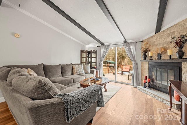 living room featuring lofted ceiling with beams, crown molding, light wood-type flooring, and a fireplace