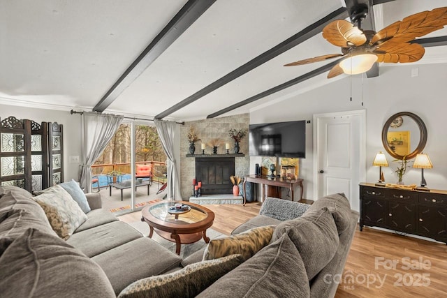 living room featuring vaulted ceiling with beams, a fireplace, and light hardwood / wood-style floors