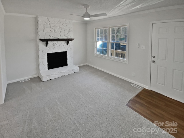 unfurnished living room with a fireplace, a textured ceiling, carpet, ornamental molding, and ceiling fan